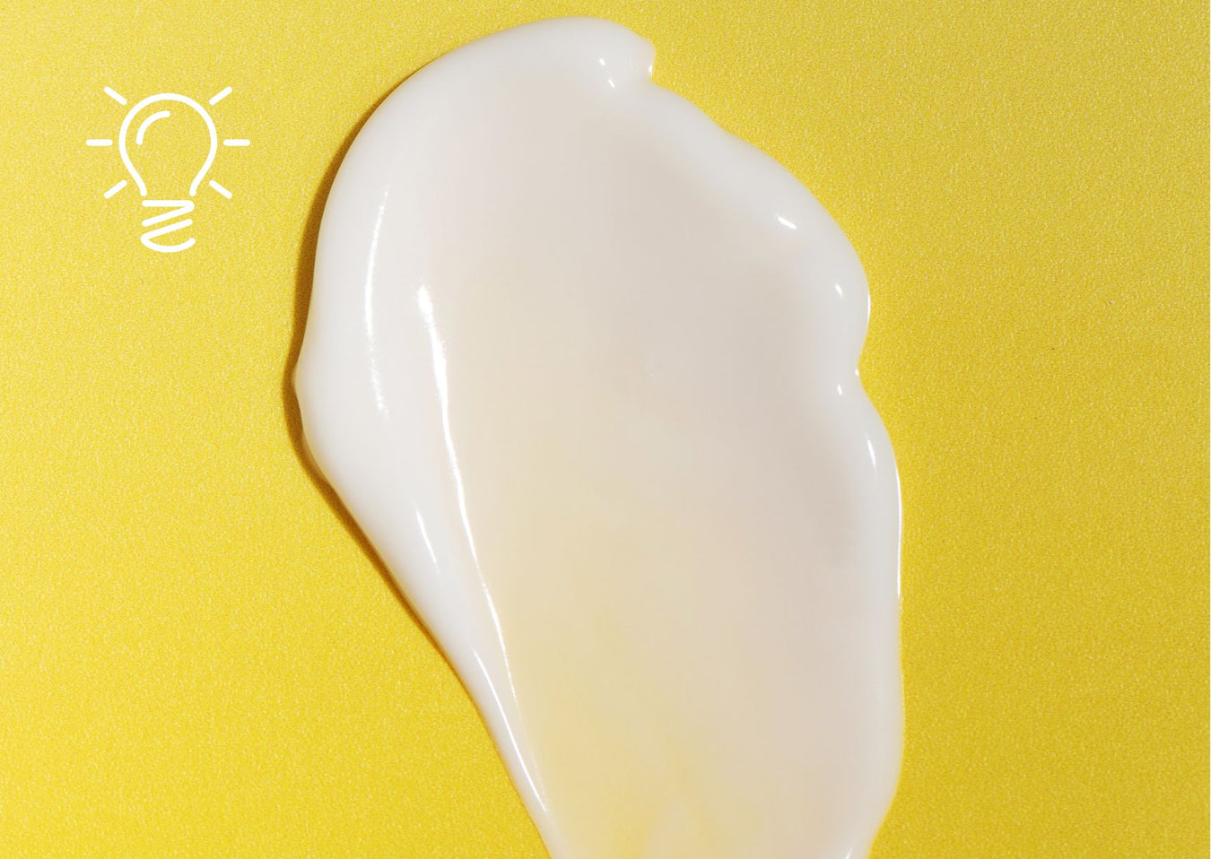 Silky swatch of Just Gentle Soothing Cream spread across a bright yellow background. Just Gentle