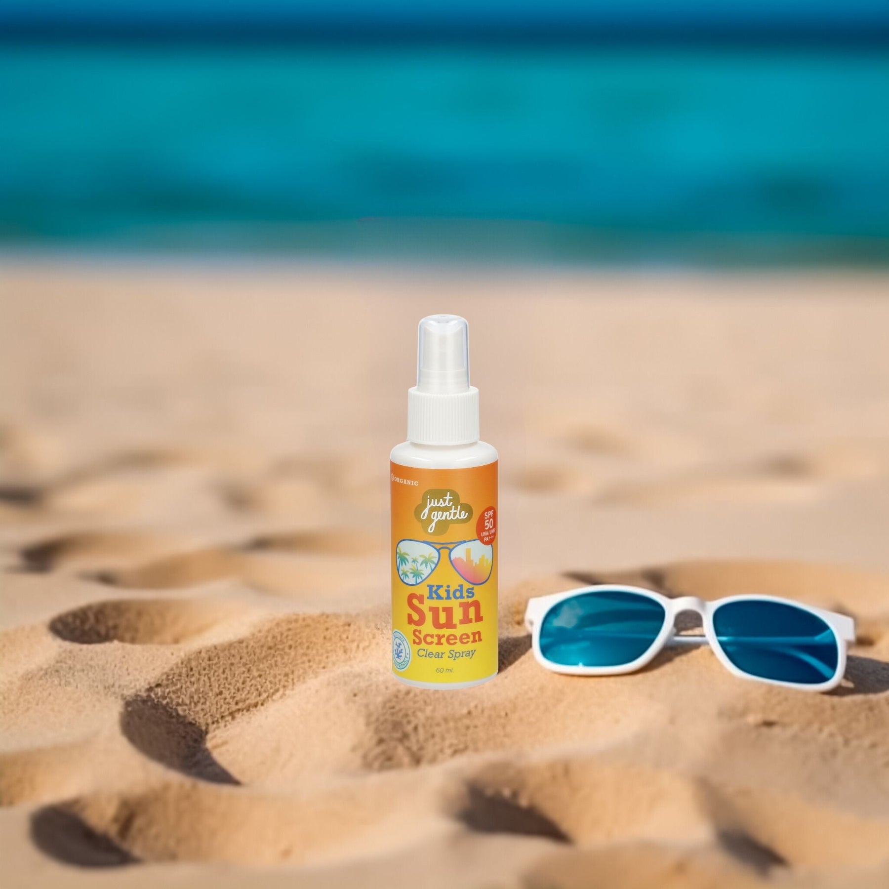 Just Gentle Kids Sunscreen Clear Spray SPF 50 PA+++ on sand beside swimming goggles