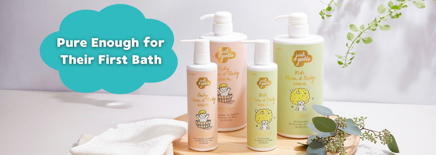 Just Gentle Baby skincare products on a wooden tray with greenery, labeled 'Pure Enough for Their First Bath'.