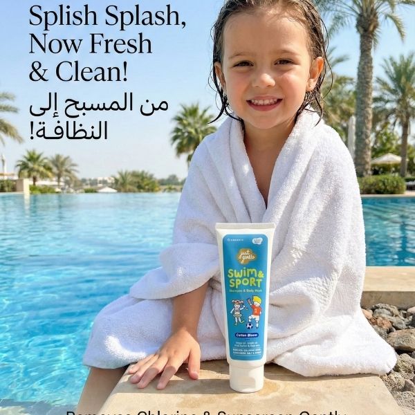 Child in a white towel holding a tube of Just Gentle swim and sport product by a pool.