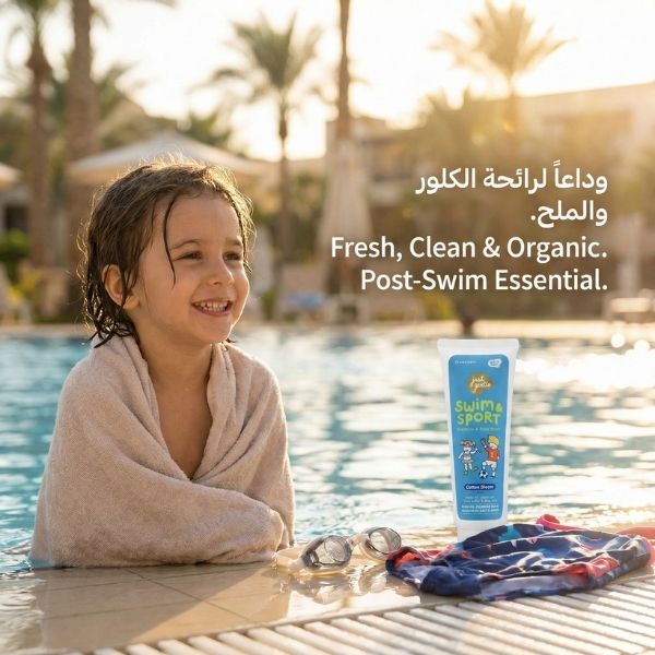 Child by a pool with a bottle of Just Gentle swim and sport product, surrounded by palm trees.