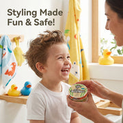 Child laughing with a container of 'Just Gentle' organic Kids' hair wax, with text 'Styling Made Fun & Safe!' in a bathroom setting.