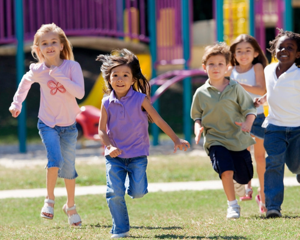 Children running on a grassy area with playground equipment in the background. Just Gentle Thumbnail for Active Life