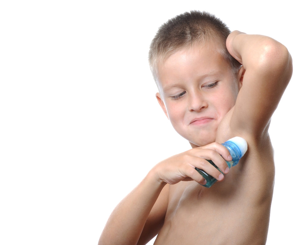 Young boy applying deodorant to his armpit on a white background. Just Gentle Confidence Shift Section